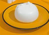 Mozzarella di Bufala fresca DOP su piatto in ceramica giallo, pronta per essere gustata.