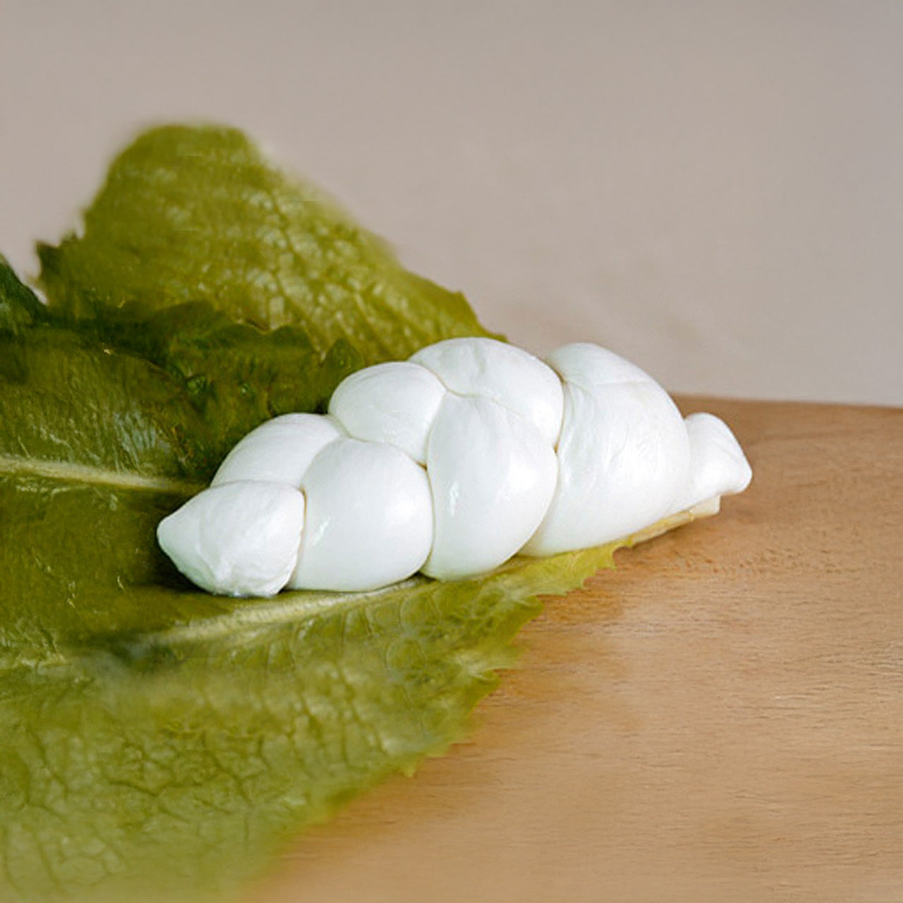 Treccia di latte di bufala Argiva posta su un piano di legno con una foglia di insalata